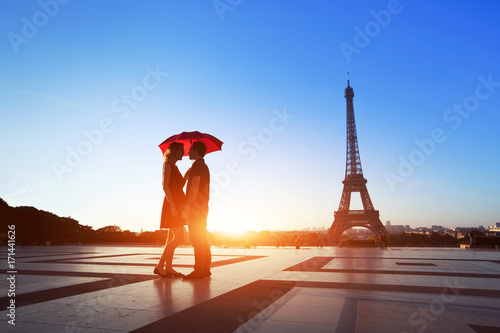romantic couple in Paris, man and woman under umbrella near Eiffel Tower, honeymoon