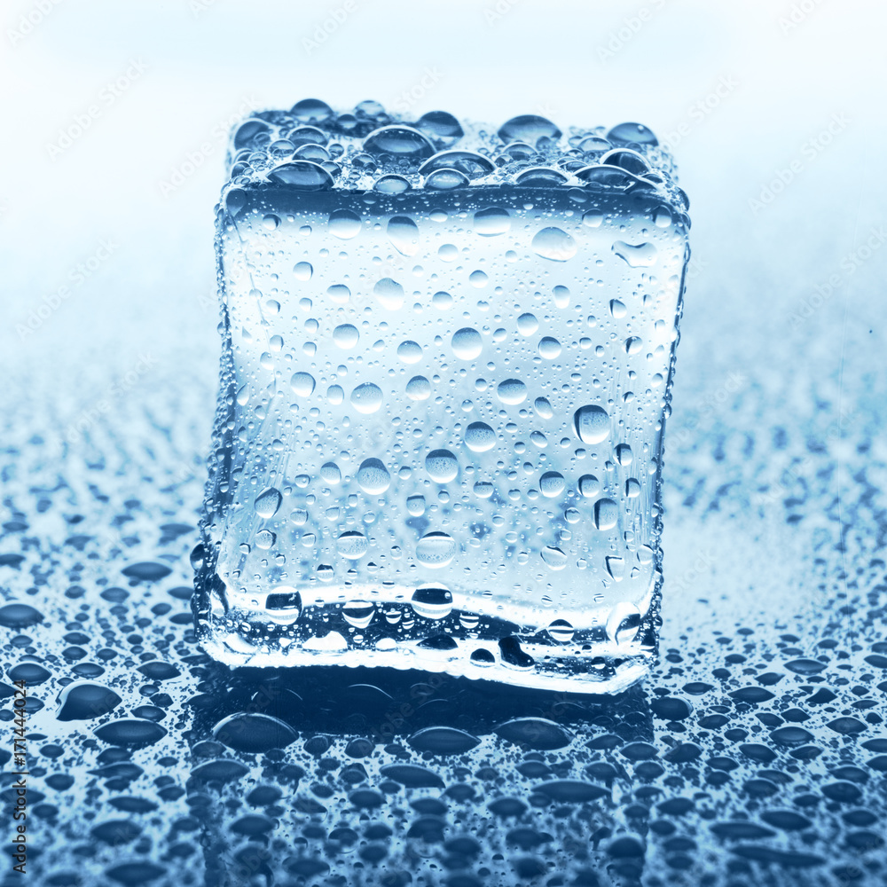 Transparent ice cube on blue glass with water drop Transparent ice cube on blue glass with water drop
