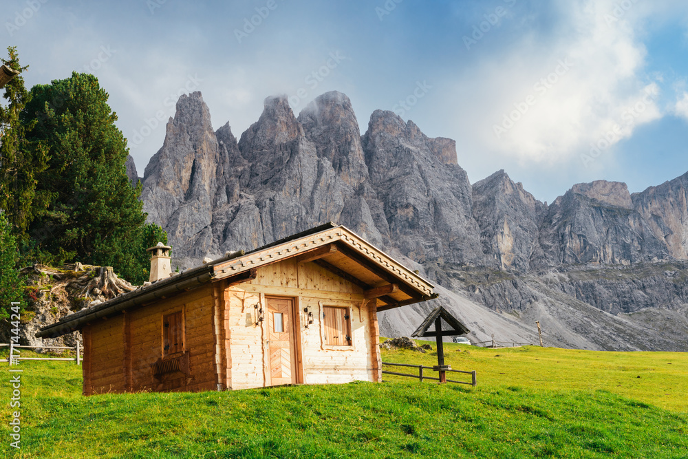 Wooden cottage overlooking the impressive Dolomites rock formation in northern Italy