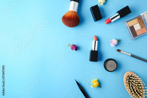 Top view of cosmetics set for makeup on a blue background. Free space for text.