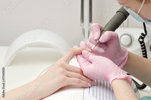 Girl in gloves handles nails with a milling cutter for manicure