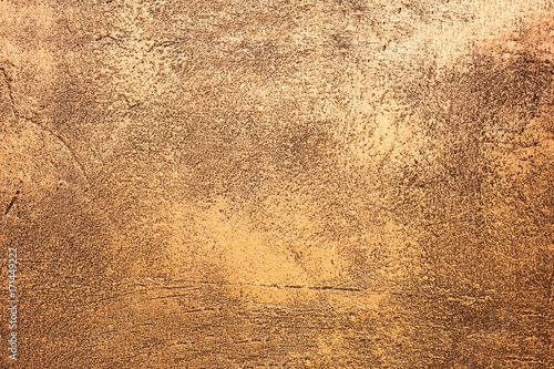 Close up texture of golden decorative plaster wall with natural light. Golden shiny background. Golden shiny plaster. Gold texture. Gold.