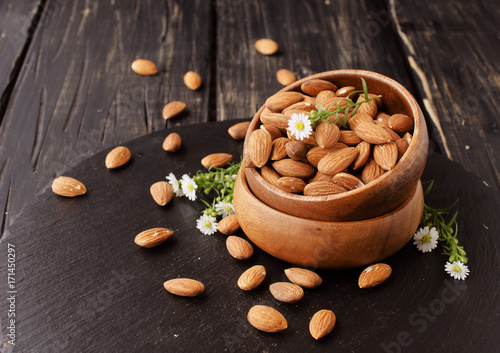 raw almonds on wooden bowl, selective focus, space for text
