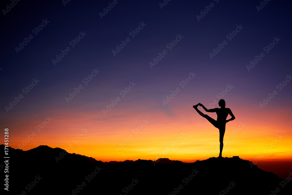 Man doing Yoga at sunset sky