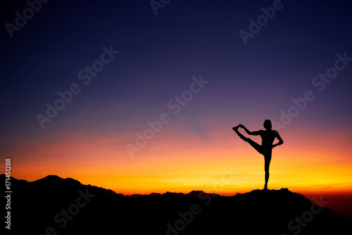 Man doing Yoga at sunset sky
