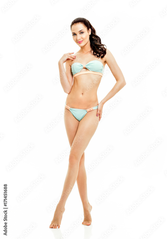 Fototapeta premium Sexy young brunette woman posing in a bikini.Beautiful perfect figure. Studio portrait. Long slim legs.