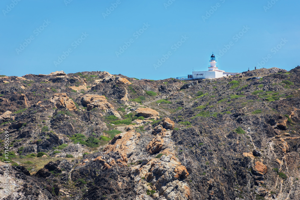 view of a lighthouse on the mountain rocks in the natural park of Cap de Creus in Catalonia (Spain)