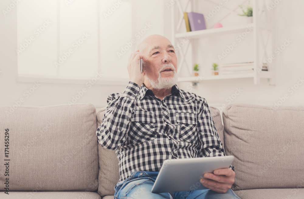 Senior man talking on phone with tablet Senior man talking on phone with tablet