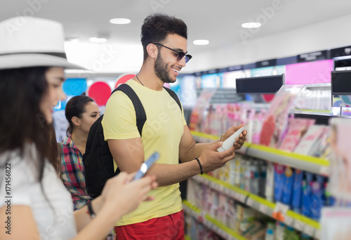 Young Couple In Supermarket Choosing Products Happy Smiling Man And Woman Buying Cosmetics Shop Interior