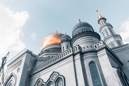 View from bottom side of beautiful Grand Cathedral Mosque made of stone: golden dome and spires with quotation from Quran, sunny autumn day, Moscow, Russia