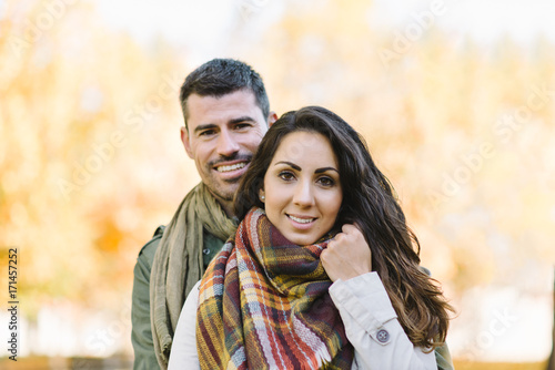 Lovely cheerful young couple portrait in autumn at the park.