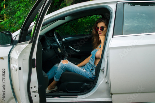 hot brunette in jeans jumpsuit sits in the car