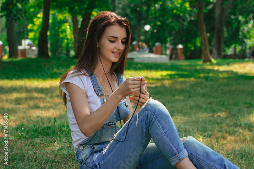 beautiful lady sitting in a park on a sunny day and listen to music