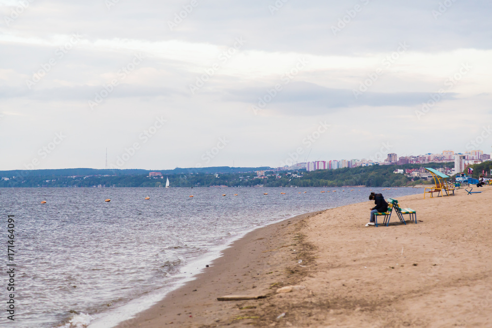 Autumn beach on the Volga. The lonely figure of a woman on the bench. The City Of Samara, Russia