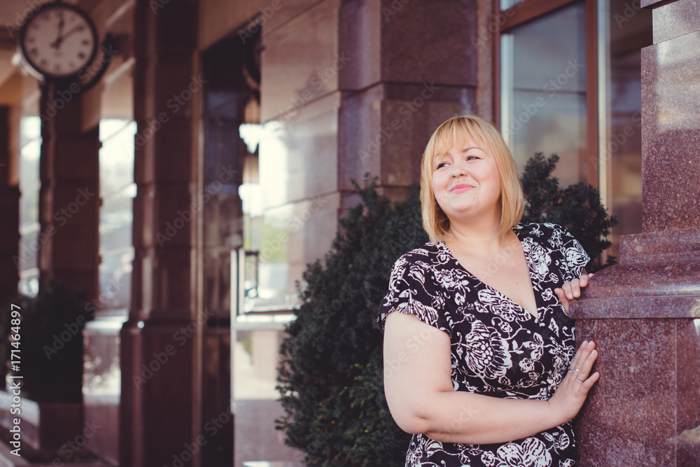 Fototapeta premium Young stylish woman walking on the city street at autumn. Casual fashion, elegant look. Plus size model. Happy overweight woman walking the city streets