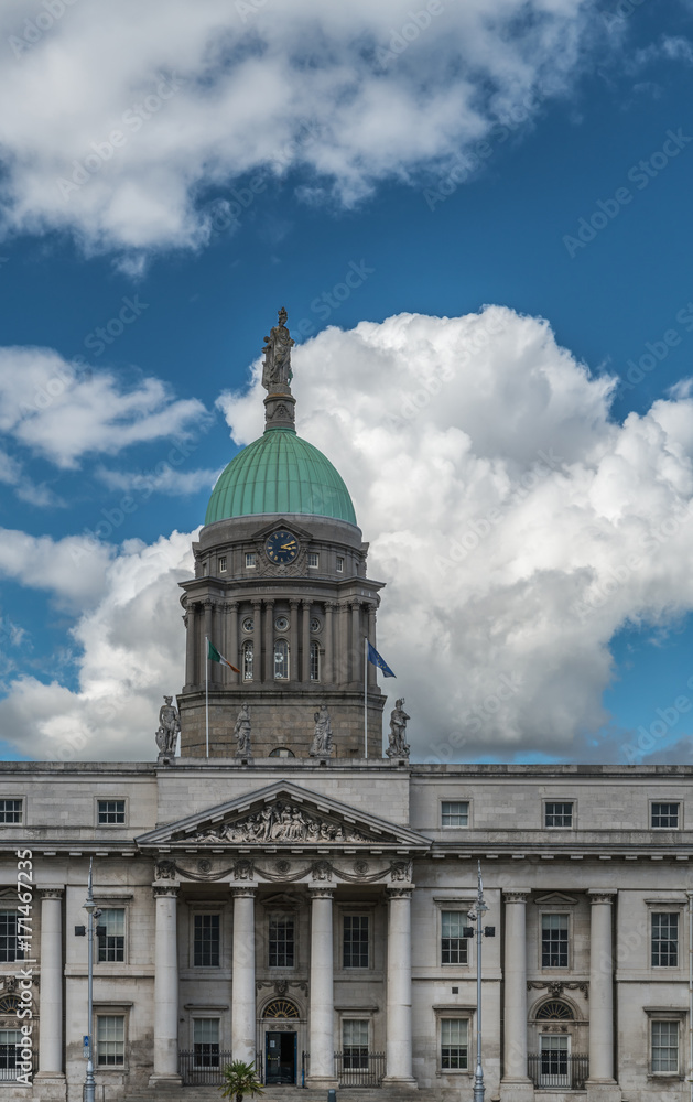 Dublin, Ireland - August 7, 2017: Central entrance section of gray stone Custom House with green dome under blue sky with white clouds.