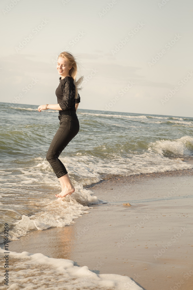 happy woman jumping in water at sunny sea beach