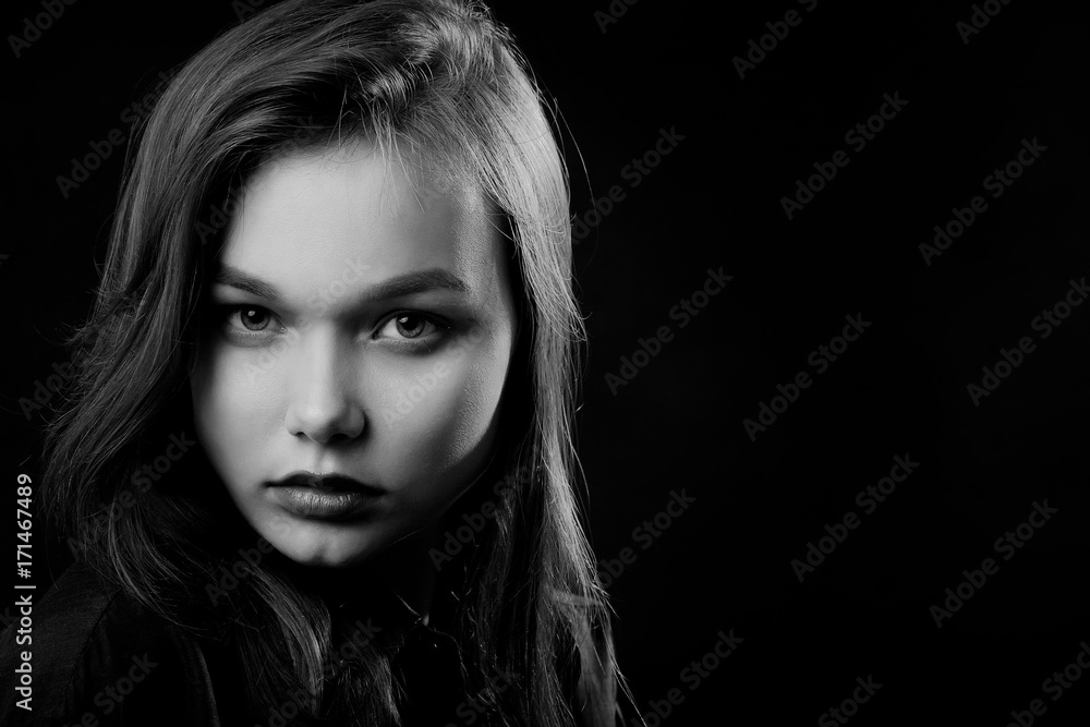 beautiful young sad woman in blouse at black background looking at camera, monochrome