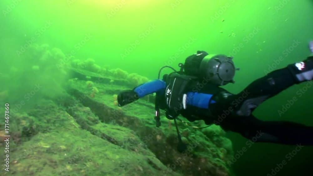 Scuba diver near rusty wreckage shipwreck on beach of White Sea Russia. Unique history place for tourism. Scuba diver near rusty wreckage shipwreck on beach of White Sea Russia. Unique history place for tourism.