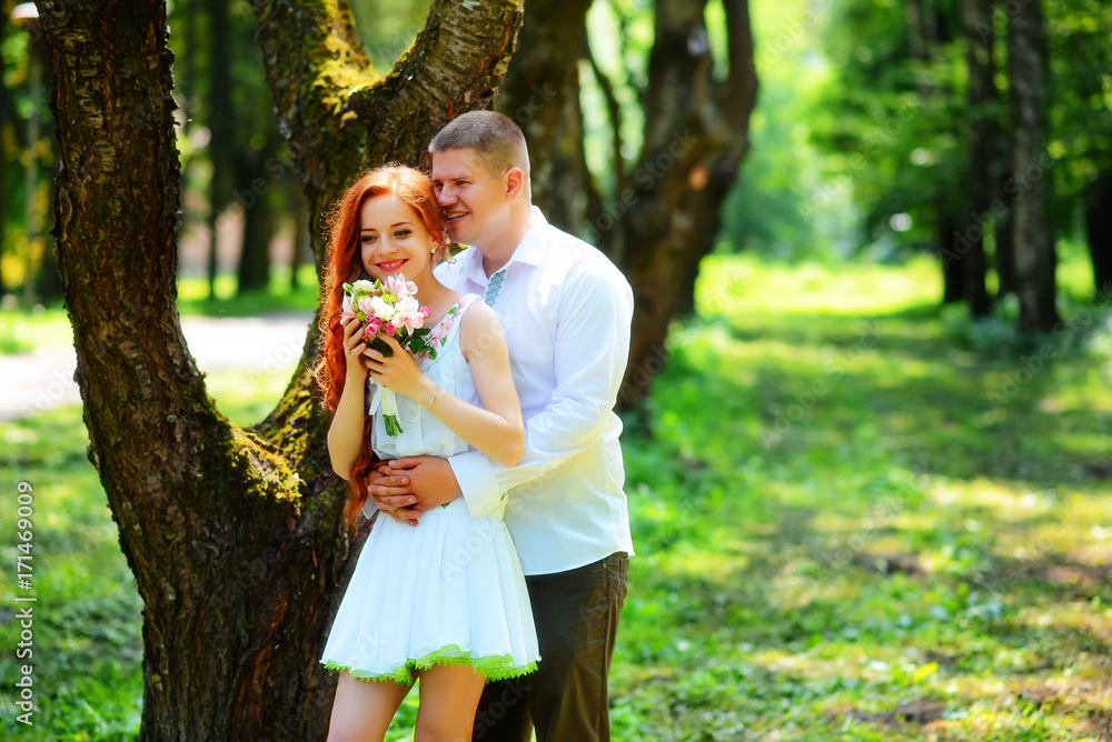 Obraz premium Bride and groom hold each other hands while they walk along the path in park.