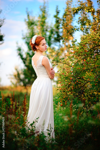 Young beautiful blonde woman in blooming garden. Bride. © cezarksv