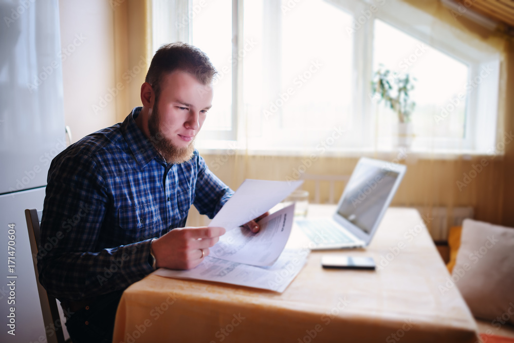 Handsome man doing some paperwork at home
