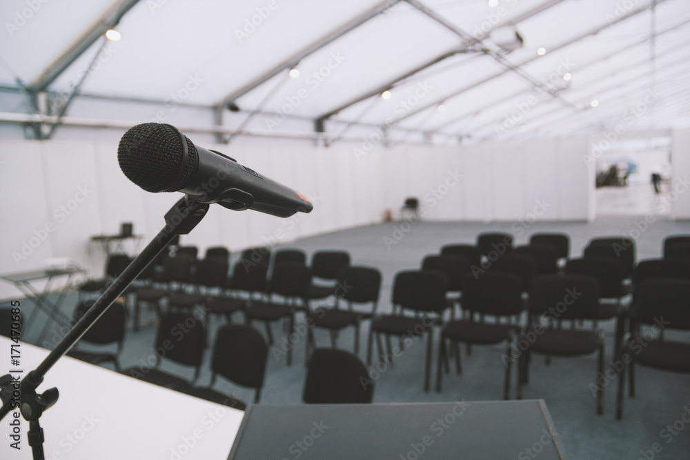 Black microphone in conference room - empty chairs on background Black microphone in conference room - empty chairs on background