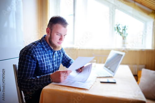 Handsome man doing some paperwork at home