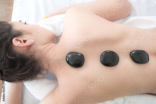 close up beautiful and healthy woman during a back stone therapy massage in spa salon