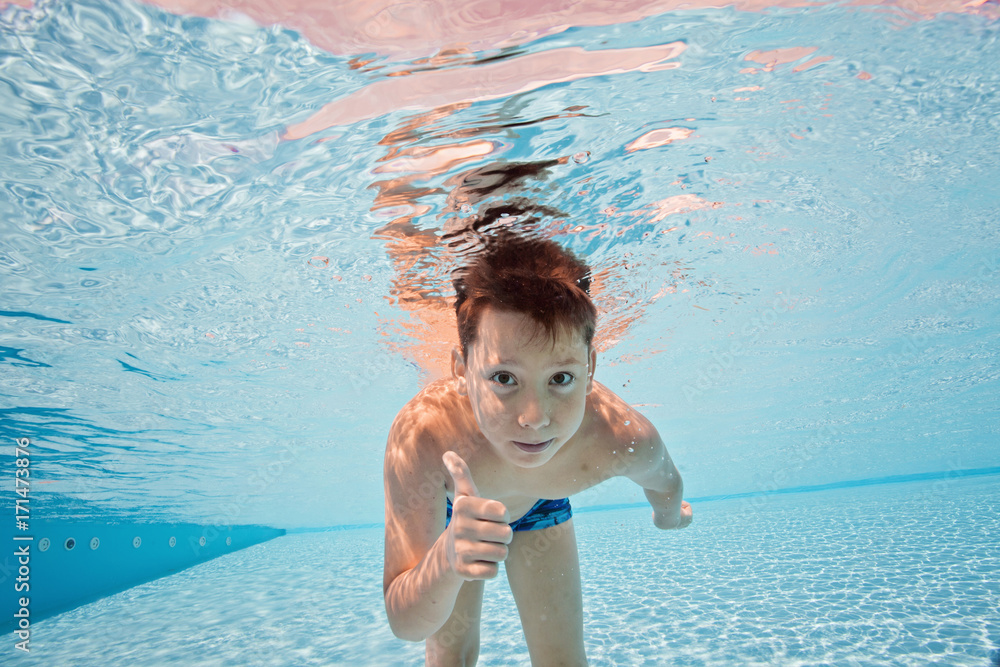 Happy young boy swim and dive underwater, kid breast stroke with fun in