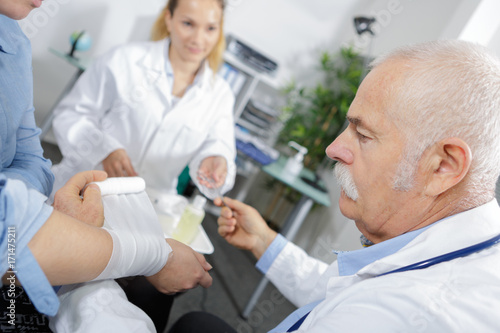 female and male doctor bandaging the arm of a patient