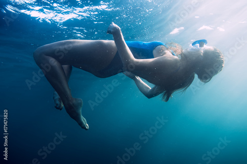 Woman floating underwater in blue ocean