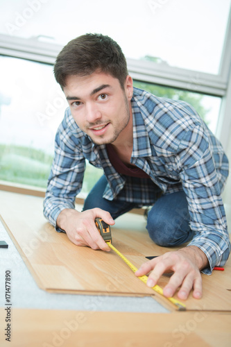 handsome carpenter taking mesurment of the wooden plate