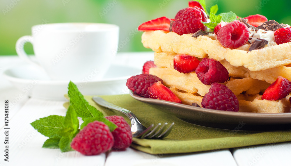 Breakfast with belgian waffles covered with raspberry and strawberry Breakfast with belgian waffles covered with raspberry and strawberry