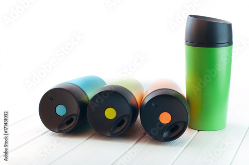 Color thermos mugs on the white wooden background with copy space