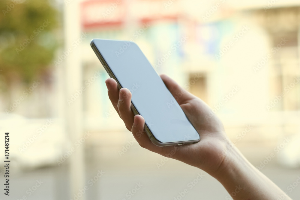 close-up of a girl holding a black phone in daylight. background blur close-up of a girl holding a black phone in daylight. background blur