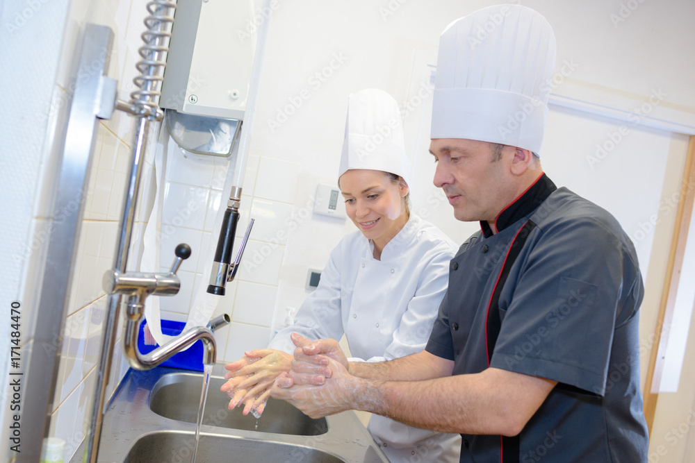 Fototapeta premium woman and man washing hands at kitchen sink