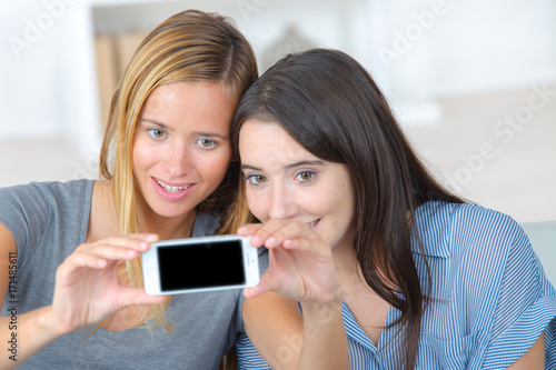 two young female friends taking a selfie indoors © auremar