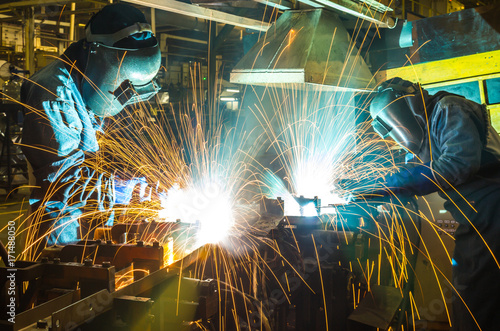 Worker, welding in a car factory with sparks, manufacturing, industry
