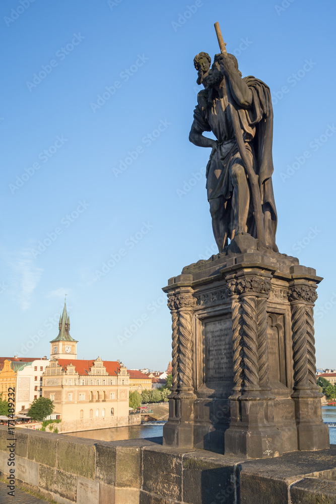 View of buildings at the Old Town and statue of Saint Christopher on the south side of the Charles Bridge (Karluv most) in Prague, Czech Republic, on a sunny day.