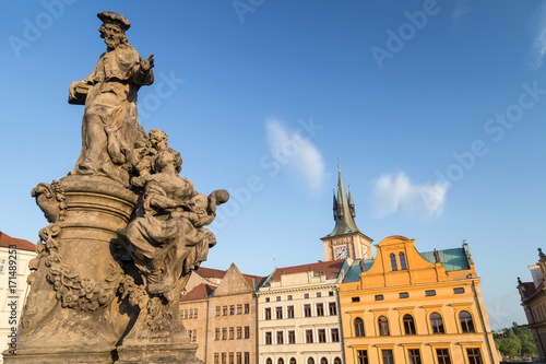 Statue of Ivo of Kermartin on the south side of the Charles Bridge (Karluv most) and buildings at the Old Town in Prague, Czech Republic, on a sunny day.