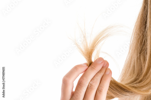 Woman's hand showing a damaged hair ends isolated on the white background. Cares about a healthy and clean hair. Beauty salon. Empty place for a text.