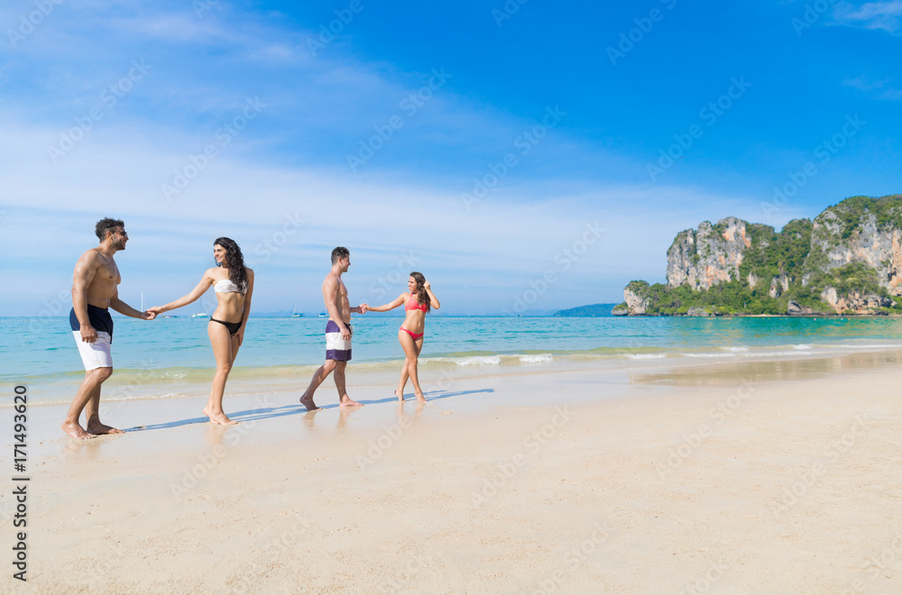 Two Couple On Beach Summer Vacation, Young People In Love Walking, Man Woman Holding Hands Sea Ocean Holiday Travel Two Couple On Beach Summer Vacation, Young People In Love Walking, Man Woman Holding Hands Sea Ocean Holiday Travel