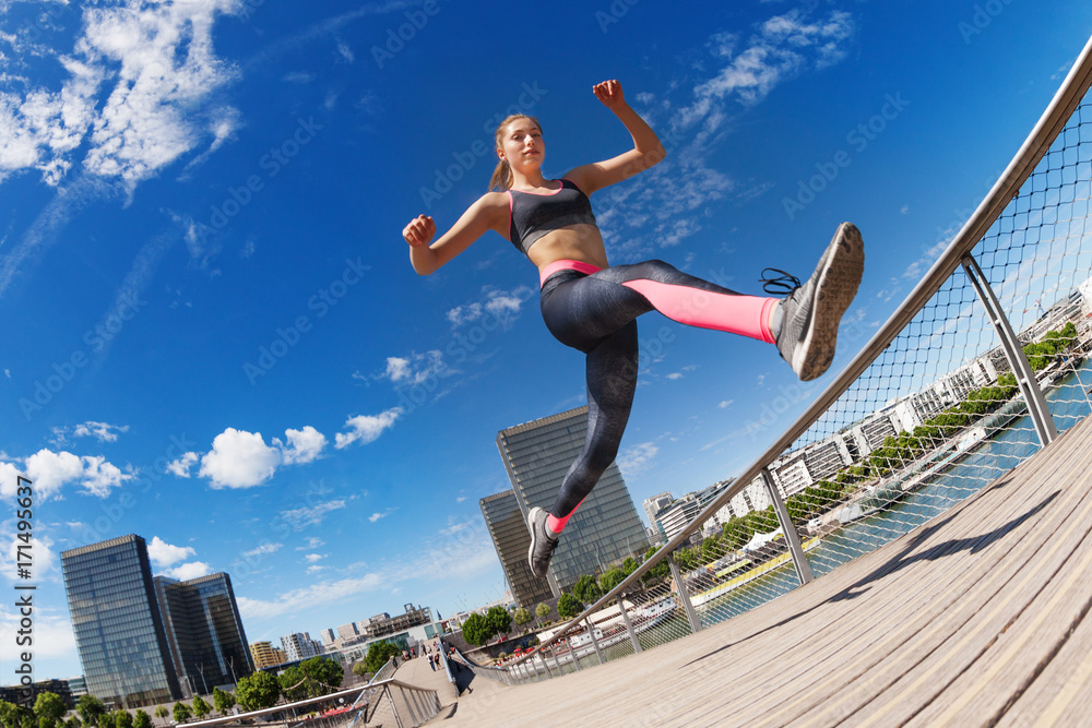 Female runner jumping while running in city