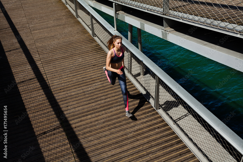 Sportswoman running and sprinting across a bridge