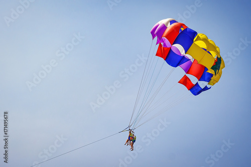 Happy couple Parasailing in Dominicana beach in summer. Couple under parachute hanging mid air. Having fun. Tropical Paradise. Positive human emotions, feelings, family, children, travel, vacation