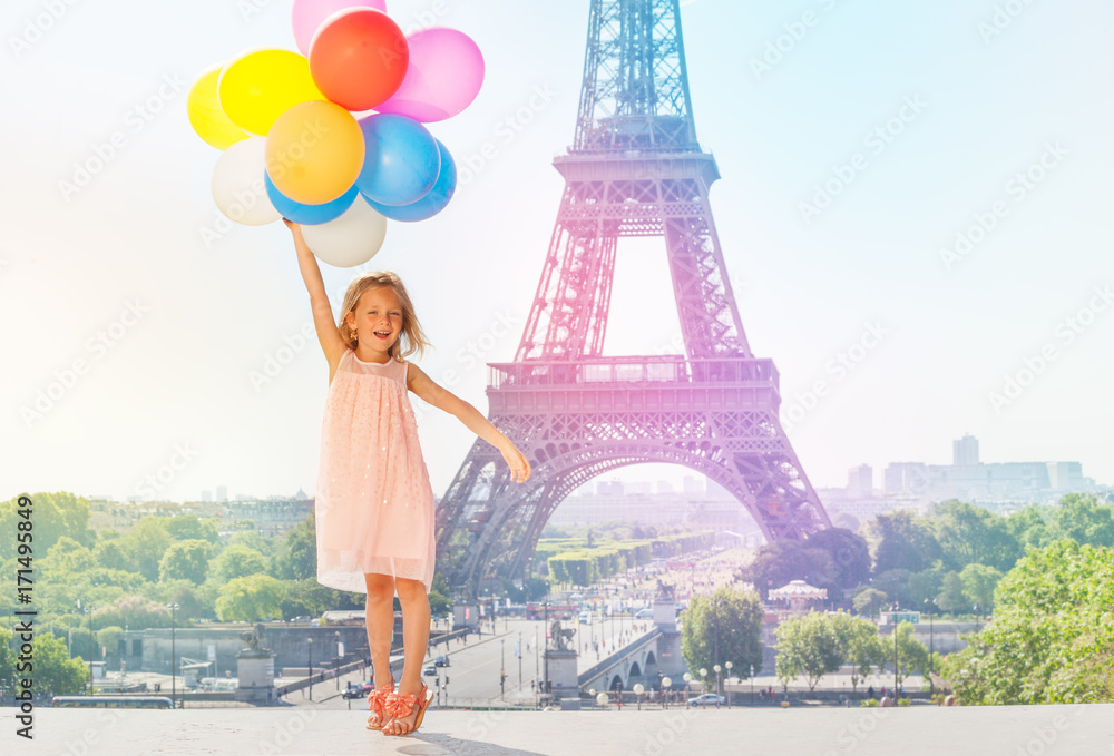 Happy little girl flying with colorful balloons
