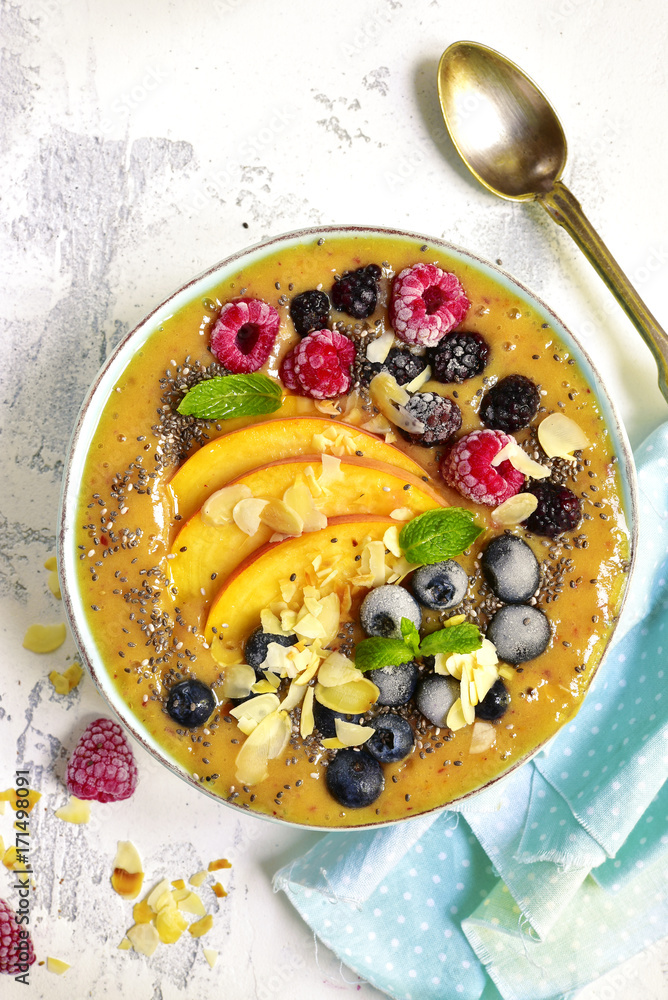 Colorful peach smoothie with wild berries and almond petals.Top view. Colorful peach smoothie with wild berries and almond petals.Top view.