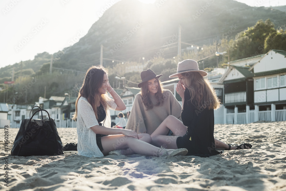 Young women relaxing at the beach at sunset Young women relaxing at the beach at sunset