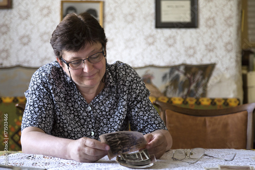 Woman looking at the old family photo while sitting in her living room photo